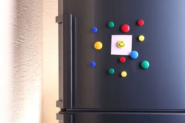 Empty paper sheets and colorful magnets on fridge door