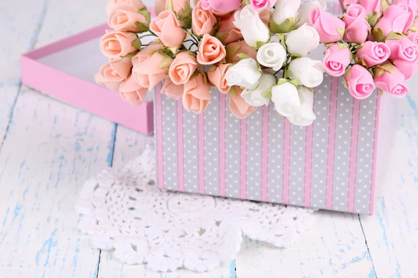 Flowers in gift box on wooden table close-up
