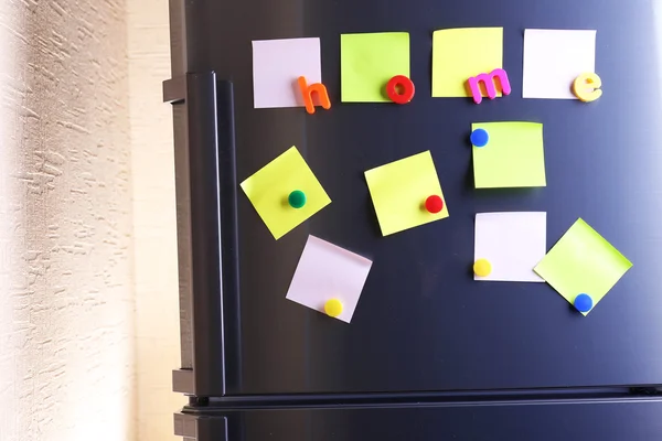 Empty paper sheets and colorful magnets on fridge door