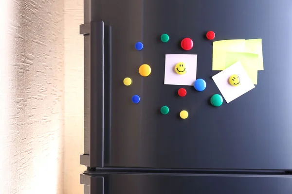 Empty paper sheets and colorful magnets on fridge door