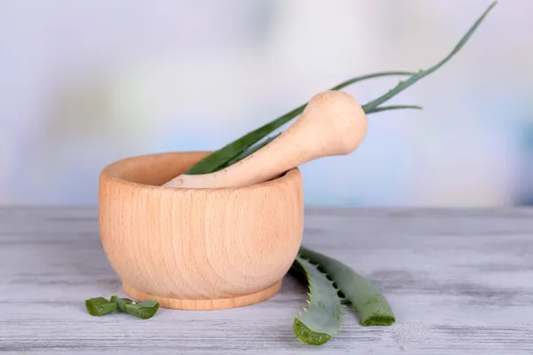 Fresh green aloe leaves in wooden mortar on wooden table
