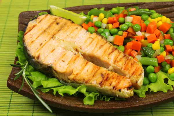 Tasty grilled salmon with vegetables, on bamboo mat