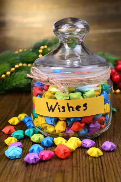 Paper stars with dreams in jar on table on wooden background