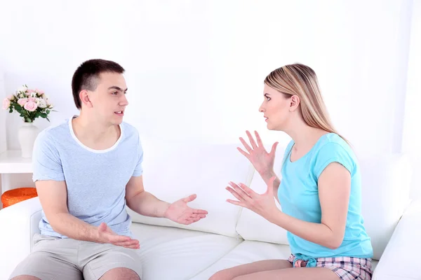 Young man and woman conflict sitting on sofa argue unhappy, on home interior background