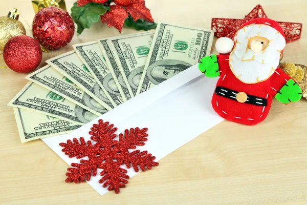 Dollar bills in envelope as gift at New year on wooden table close-up