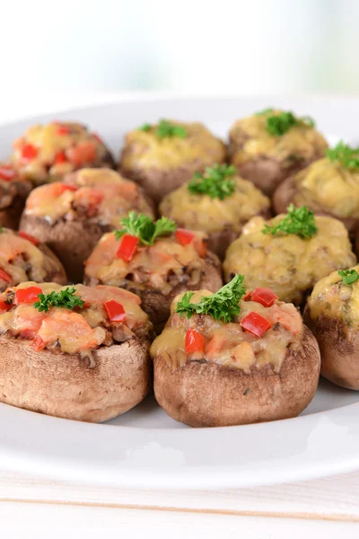 Stuffed mushrooms on plate on table on light background