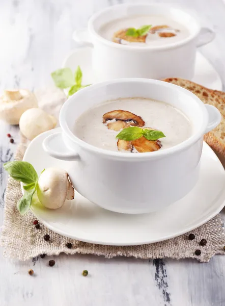 Mushroom soup in white pots, on napkin, on wooden background