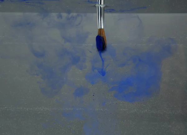 Brush with color paint in water