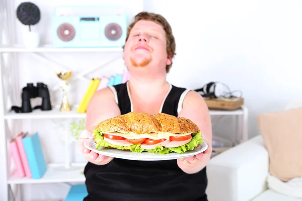 Fat man eating sandwich
