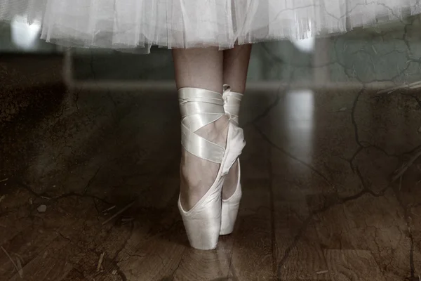 Ballerina legs in pointes in dark dancing hall