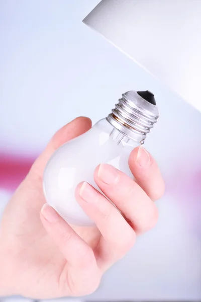 Hand changing light bulb for lamp at home