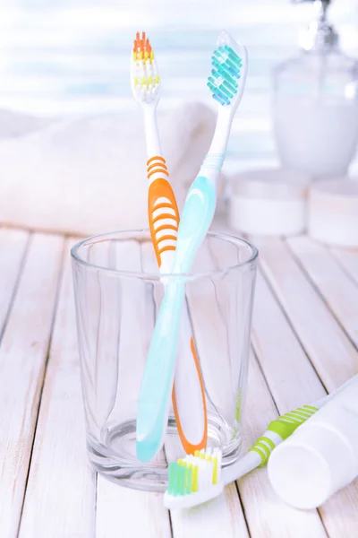 Toothbrushes in glass on table on light background