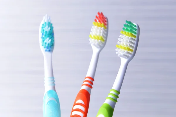 Toothbrushes in glass on table on light background