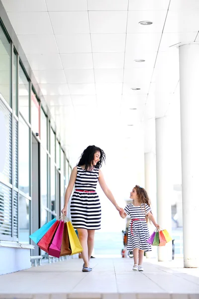 Happy mom and daughter with shop bags, outdoors