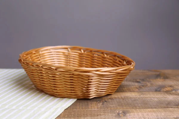 Empty wicker basket on wooden table, on dark background