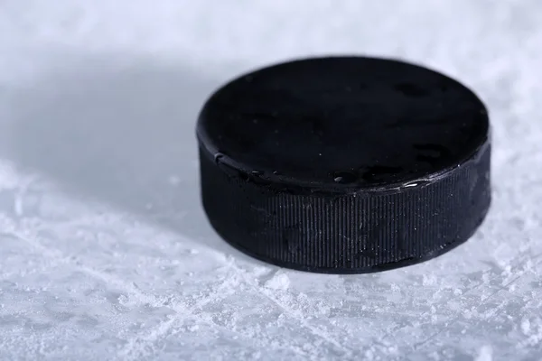 Black hockey puck on ice rink background