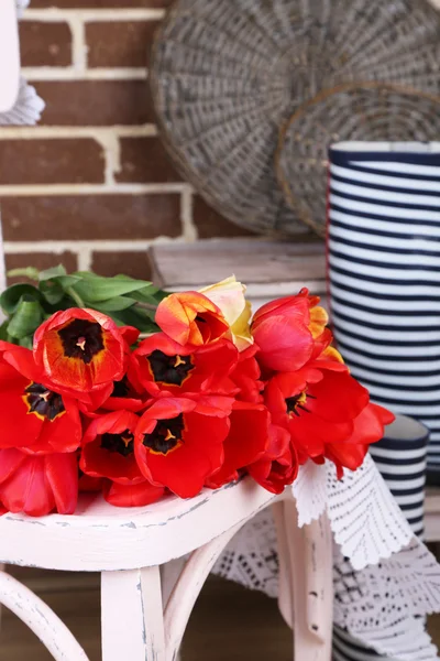 Bouquet of colorful tulips on chair, on home interior background