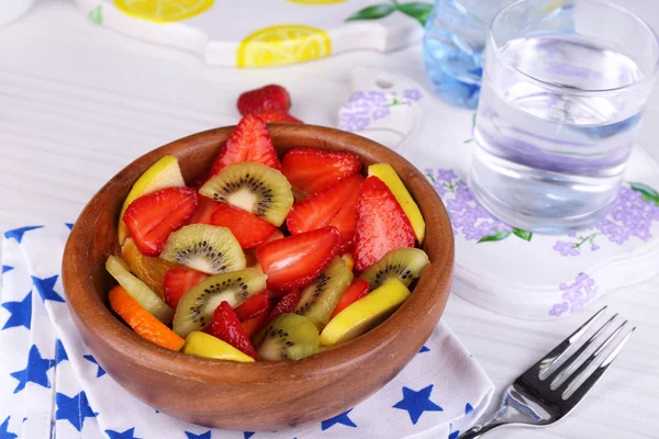 Various sliced fruits in bowl on table close-up