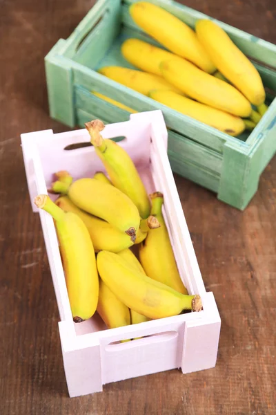 Bunch of mini bananas in wooden boxes on wooden background