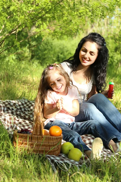 Happy mom and daughter. Picnic in the green park