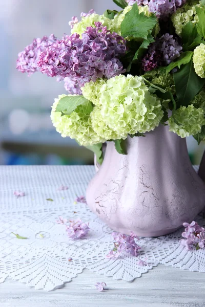 Composition with tea mugs and beautiful spring flowers in vase, on wooden table, on bright background