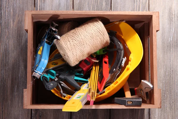 Wooden box with different tools, on wooden background