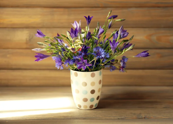 Beautiful wild flowers on table on wooden background
