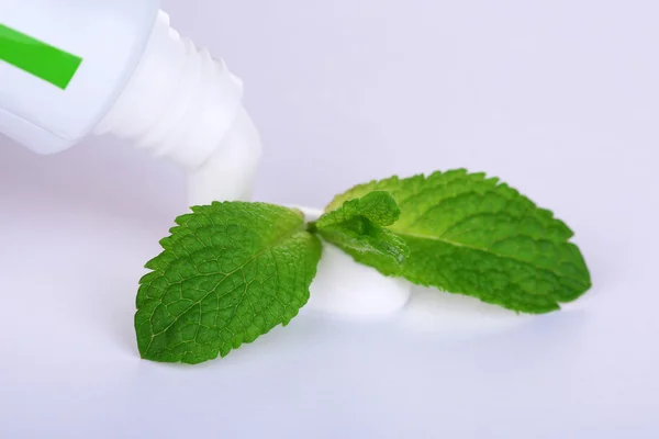 Toothpaste squeezed from tube, mint leaves, close-up, isolated on white