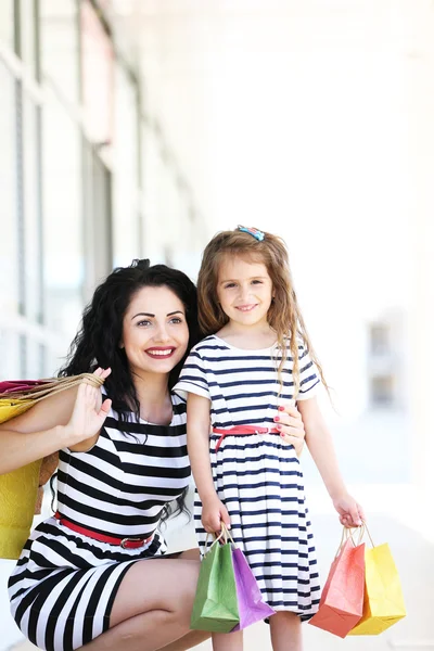 Happy mom and daughter with shop bags, outdoors