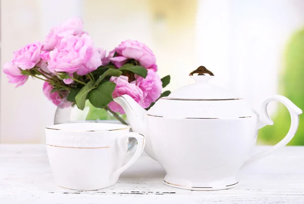 Breakfast tea with  teapot of fresh pink garden roses on bright background
