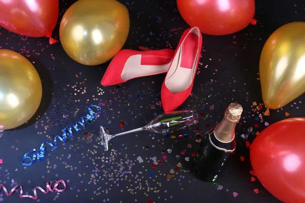 Shoes with confetti, champagne and balloons on the floor