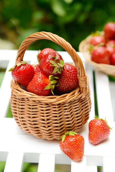 Ripe sweet strawberries in wicker basket on table in garden