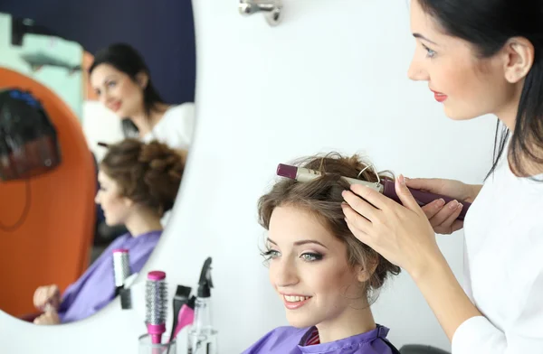 Woman hairdresser do hairstyle girl