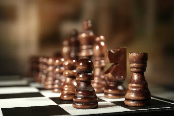 Chess board with chess pieces on brown background