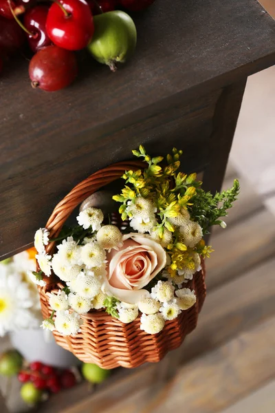 Basket of flowers hanging on wooden shelf close up