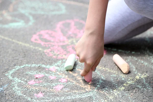 Girl drawing with chalk on asphalt