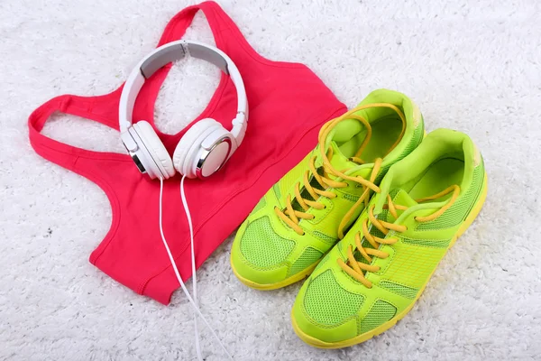 Sport clothes, shoes and headphones on white carpet background.