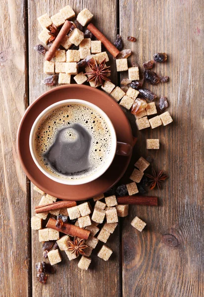 Brown sugar, spices and cup of coffee on wooden background