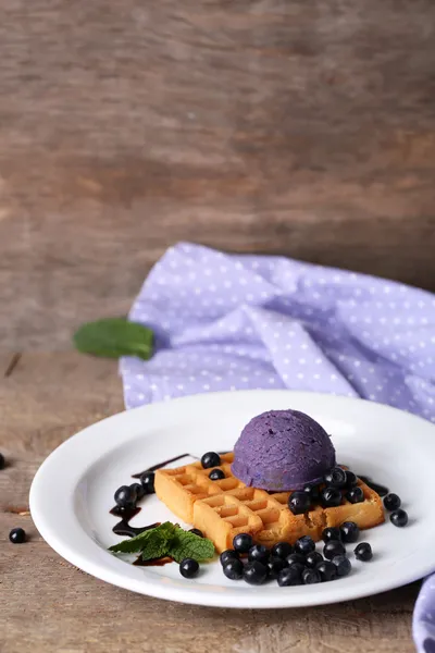 Tasty belgian waffles with ice cream on wooden table