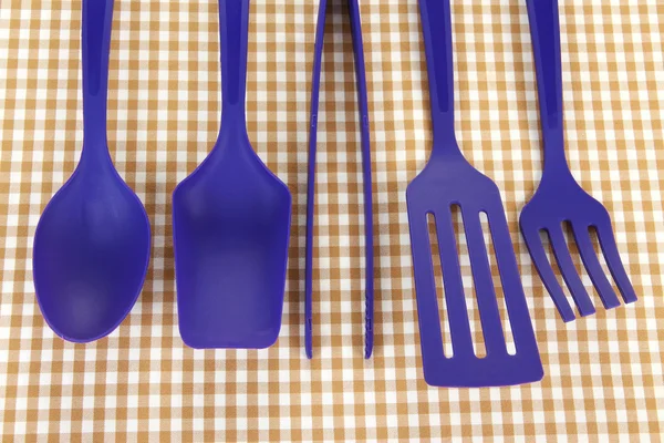 Plastic kitchen utensils on fabric background