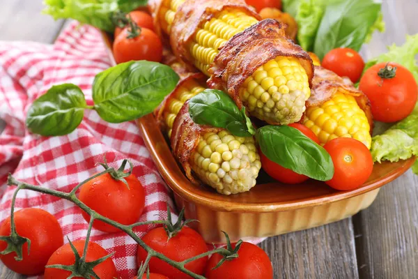 Grilled bacon wrapped corn on table, close-up