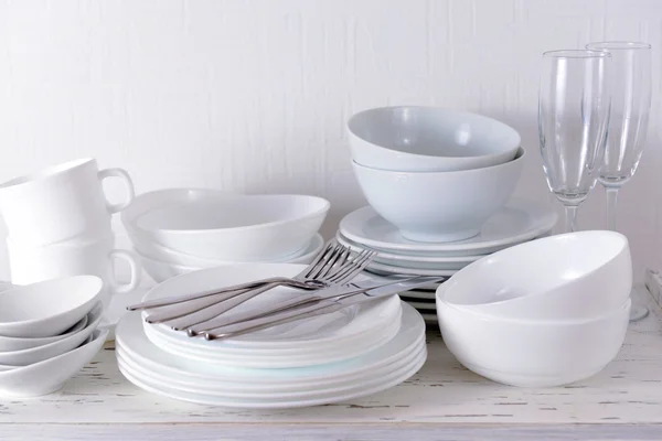 Set of white dishes on table on light background