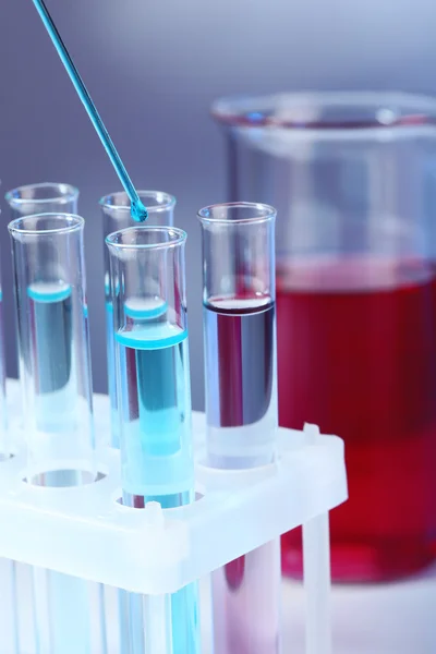 Test tubes with blue liquid and glass with red liquid on light background