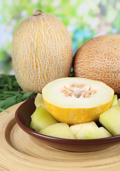Melon on brown plate on bamboo plate on grass on natural background