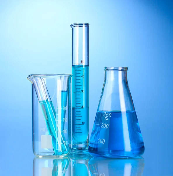 Laboratory glassware with blue liquid with reflection on blue background