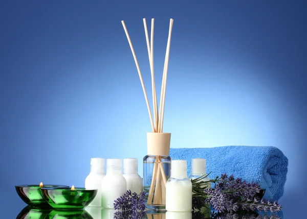 Bottle of air freshener, lavander, towel and candles on blue background