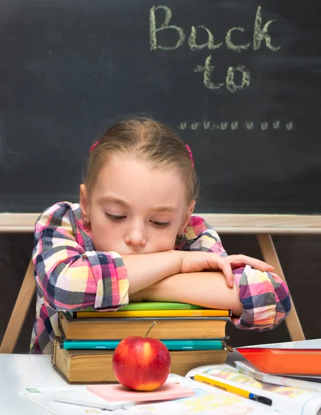 Portrait of sad schoolgirl with books and apple. School concept.