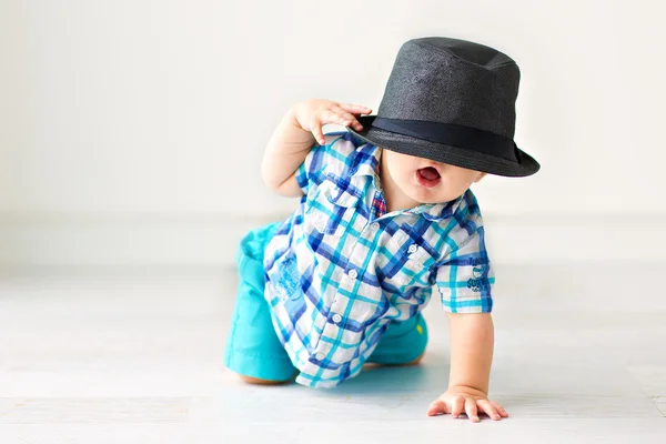 Cute baby sitting on the floor in a hat