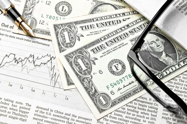 Detail of dollars near glasses and golden pen