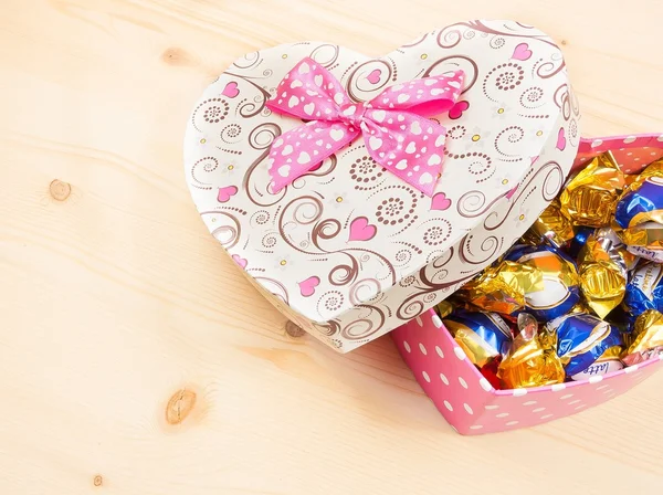 Chocolate candies in gift box on wood table, concept of valentine day